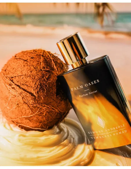 Flacone di Palm Oases Simone Andreoli appoggiato su sabbia bianca con una palma e mare turchese sullo sfondo, luci calde del tramonto – L'Atelier dei Profumi Teramo.