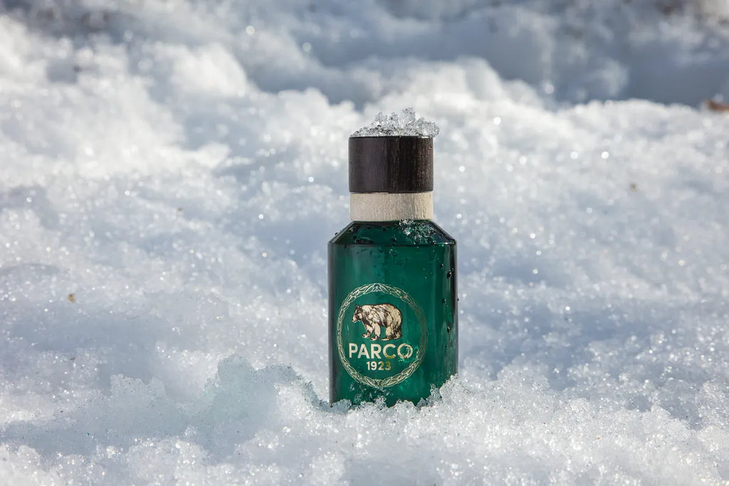 Dettaglio Eau De Toilette Parco 1923 appoggiata sulla neve nel bosco - Profumo naturale d'Abruzzo - Rivenditore Autorizzato.